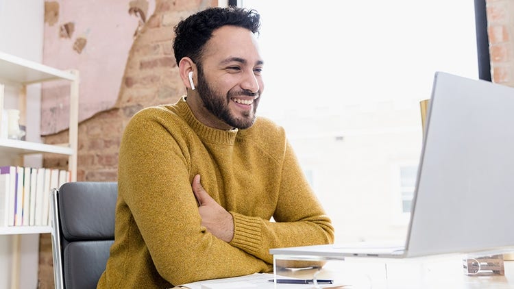 Smiling employee taking a Traliant course at his computer